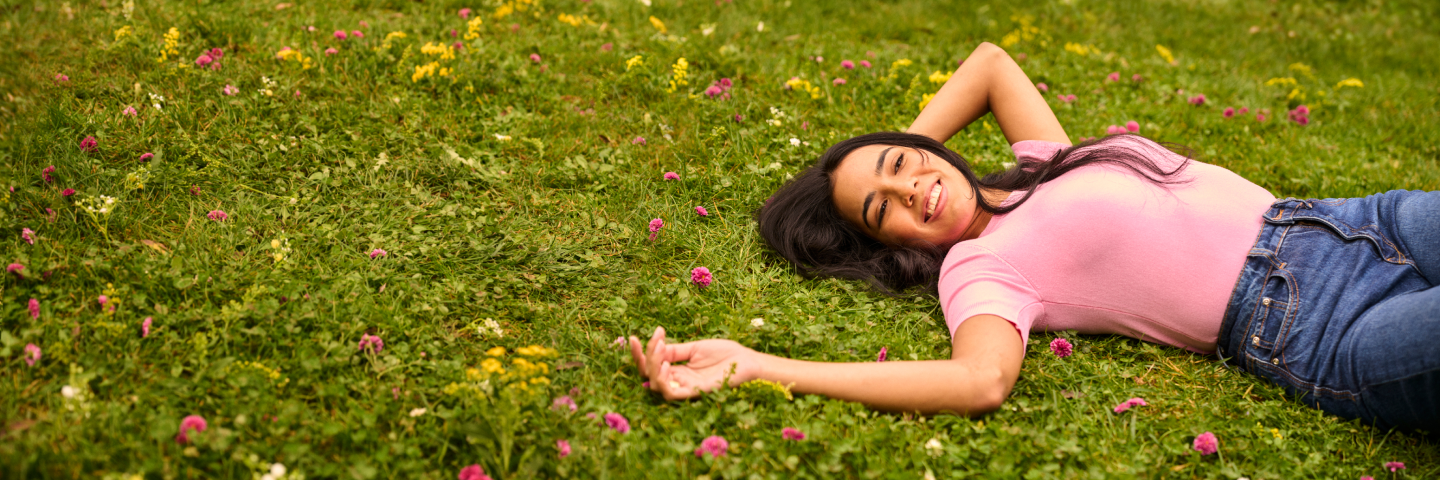 Woman relaxing in a field of flowers, carefree and free from allergy symptoms.