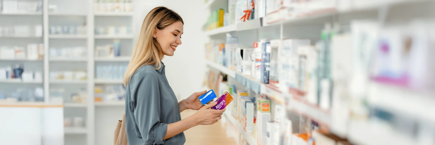 Woman in the pharmacy choosing between Allegra and a competitor product