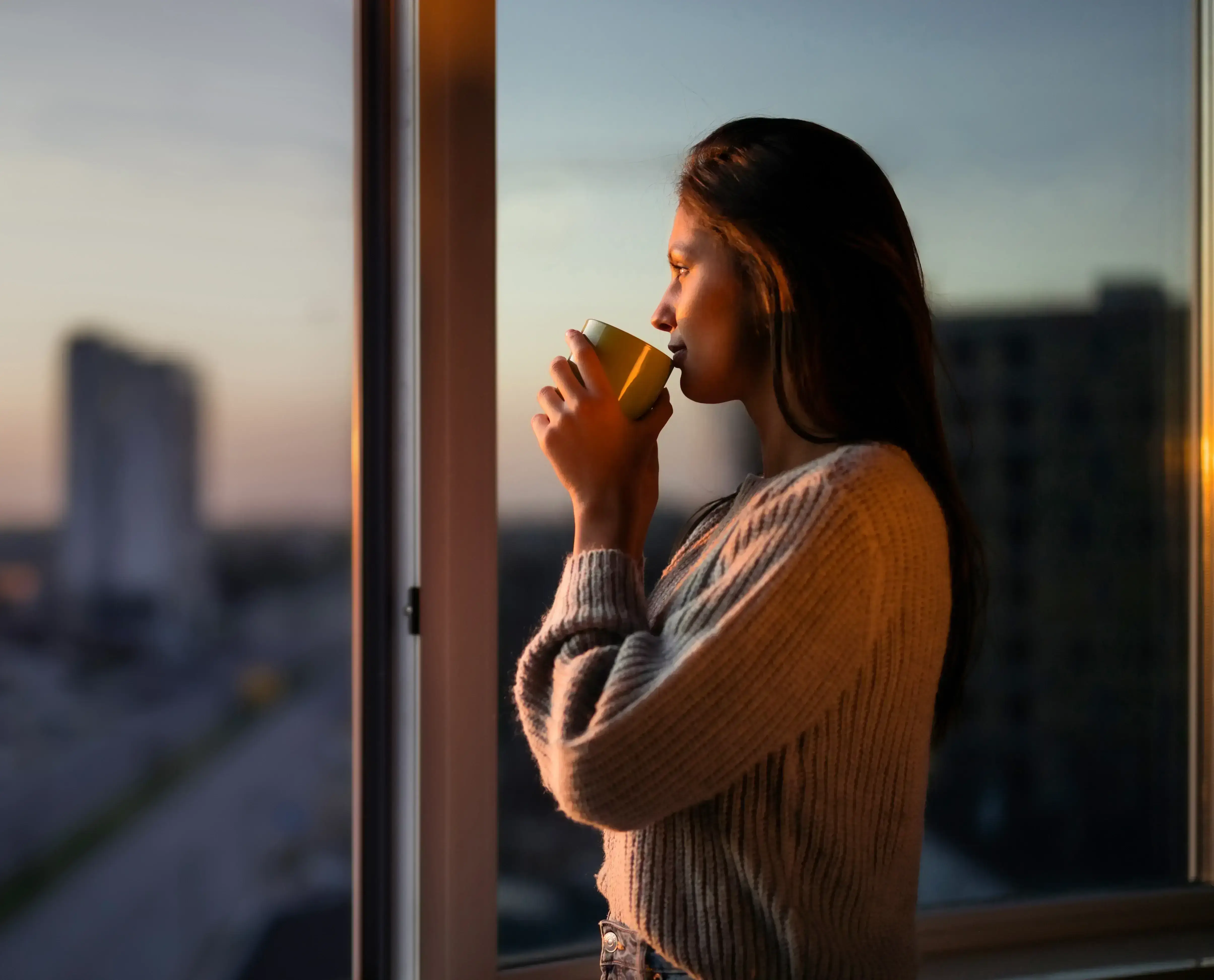 Kobieta przy oknie pijąca z kubka
