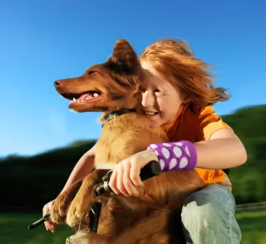 Happy child embracing their dog outdoors, suggesting pet fur as an allergy trigger